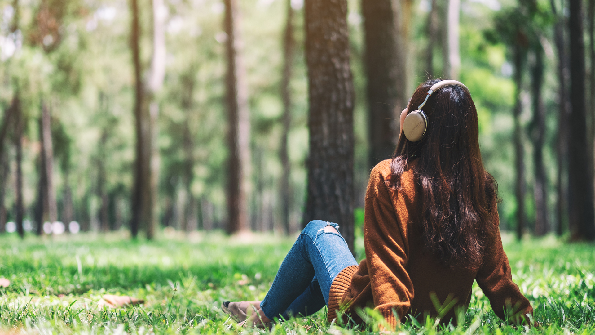 A beautiful asian woman enjoy listening to music with headphone with feeling happy and relaxed in the park